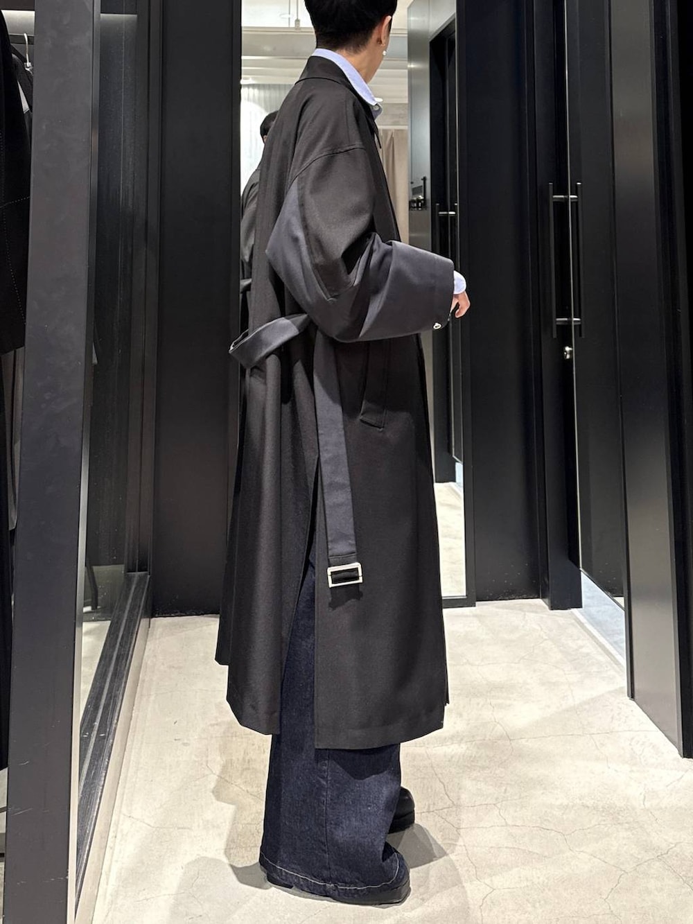 ブラック系のブーツ、ブルー系のデニムパンツ、ブラック系のトレンチコートを着用したメンズの冬コーディネートの2枚目の写真