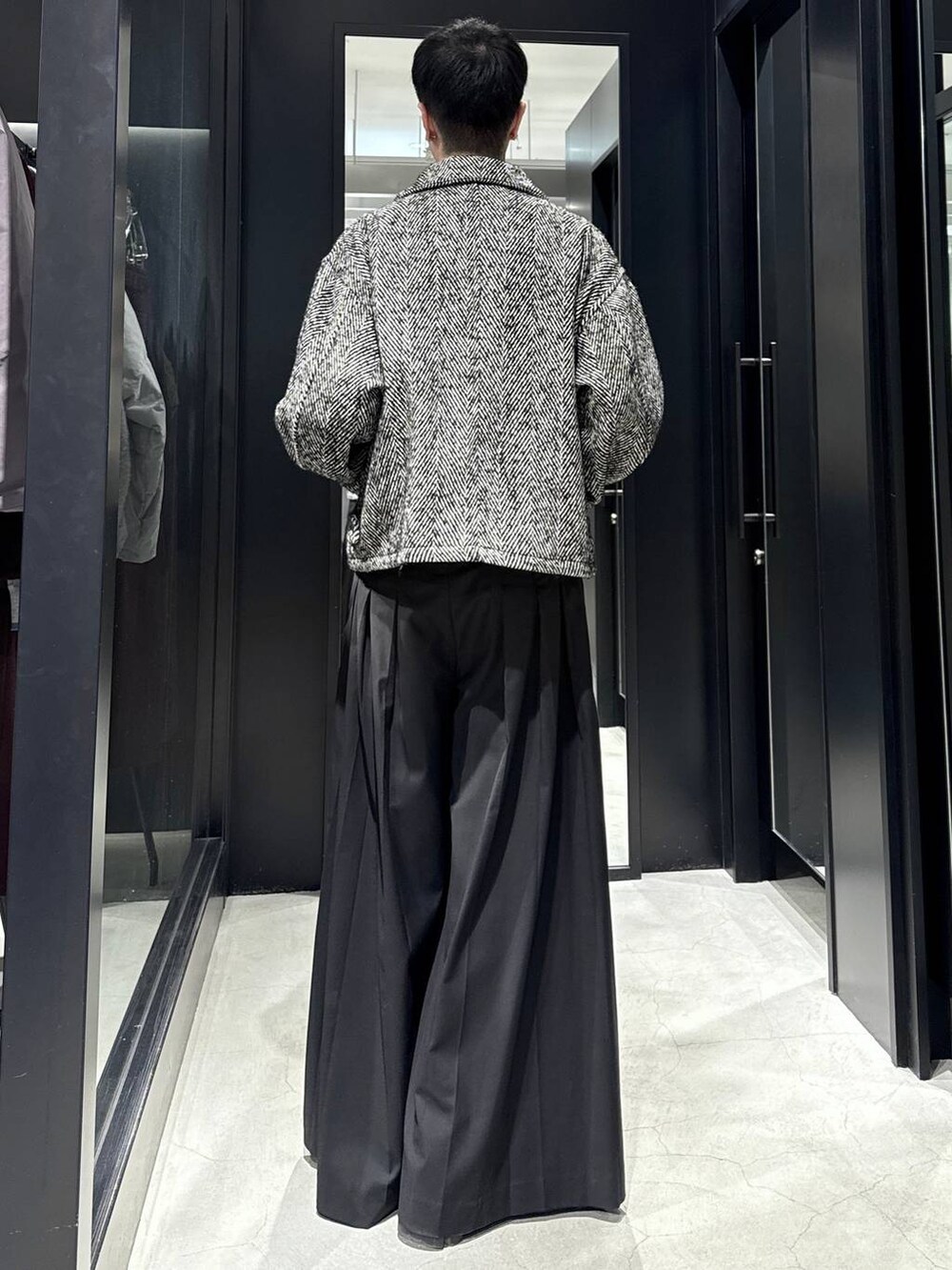 グレー系のブルゾン、ブラック系のスラックスを着用したメンズの冬コーディネートの3枚目の写真