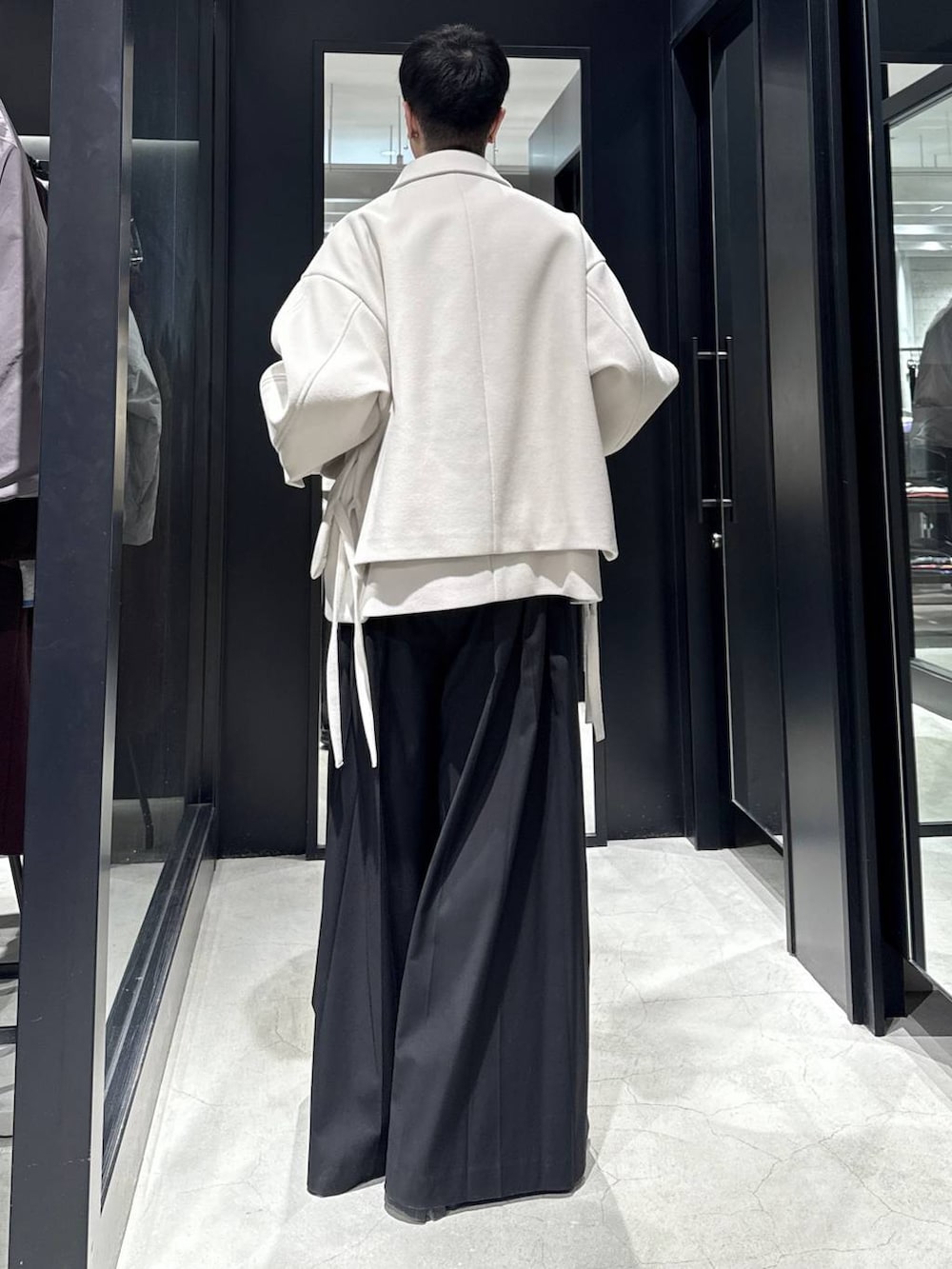 ホワイト系のブルゾン、ブラック系のスラックスを着用したメンズの冬コーディネートの3枚目の写真