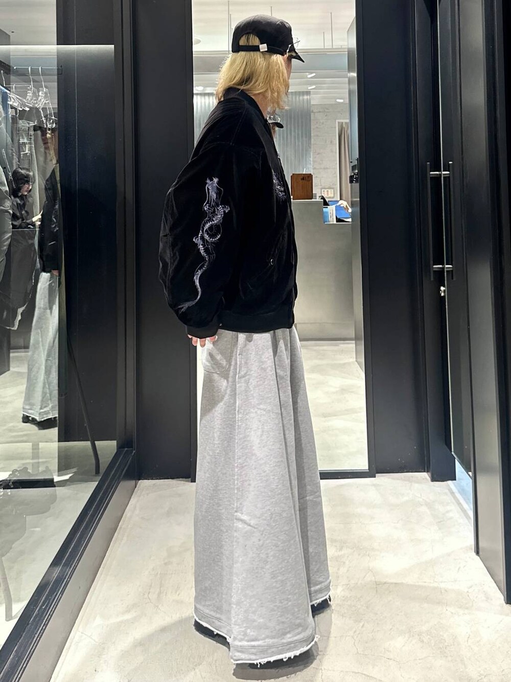 グレー系のスウェットパンツ、ブラック系のブルゾン、ブラック系のキャップを着用したメンズの秋コーディネートの2枚目の写真