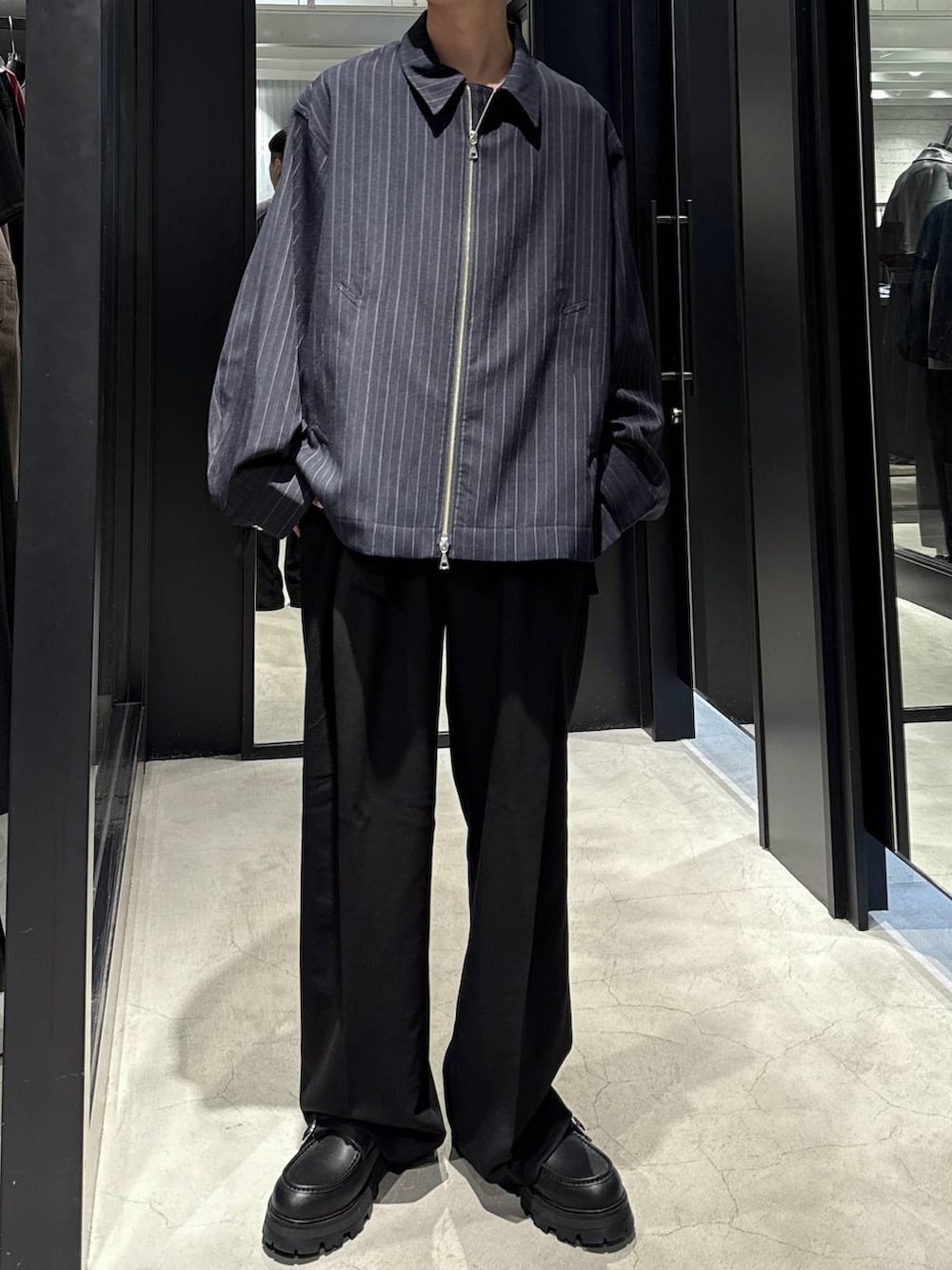 ブルー系のブルゾン、ブラック系のTシャツ/カットソー、ブラック系のドレスシューズを着用したメンズの秋コーディネートの4枚目の写真