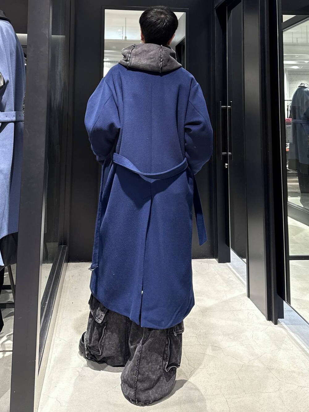 ブルー系のチェスターコート、ブラック系のパーカー、ブラック系のスウェットパンツを着用したメンズの冬コーディネートの3枚目の写真