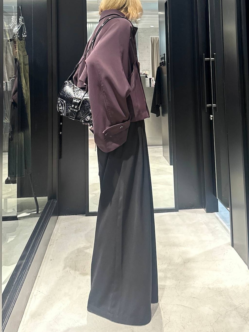 レッド系のブルゾン、ブラック系のショルダーバッグ、ブラック系のスラックスを着用したメンズの秋コーディネートの2枚目の写真