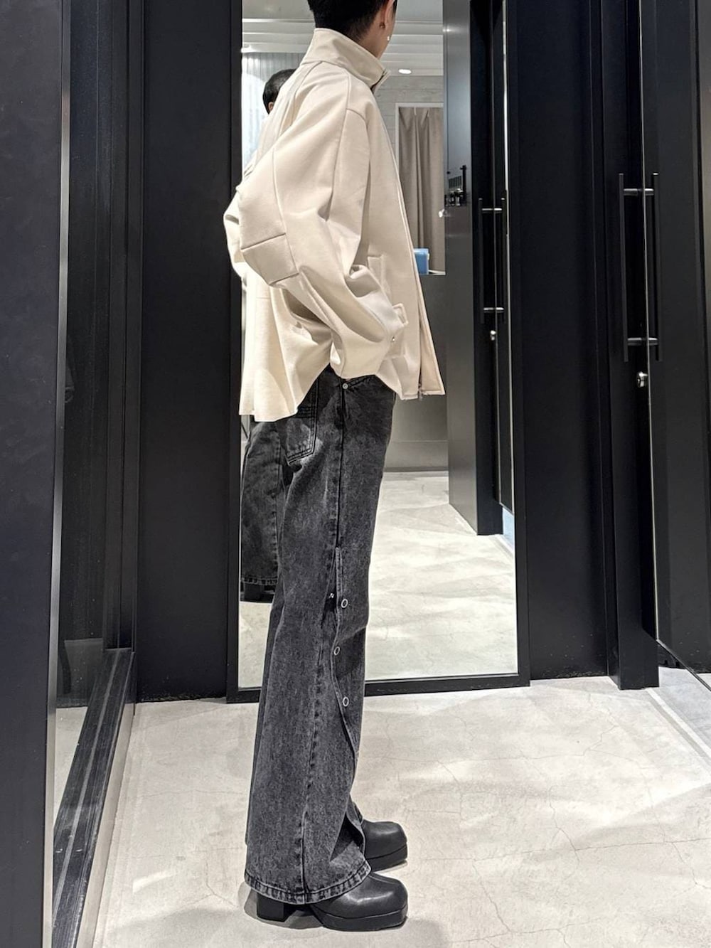 ブラック系のブーツ、ホワイト系のブルゾン、ブラック系のデニムパンツを着用したメンズの冬コーディネートの2枚目の写真