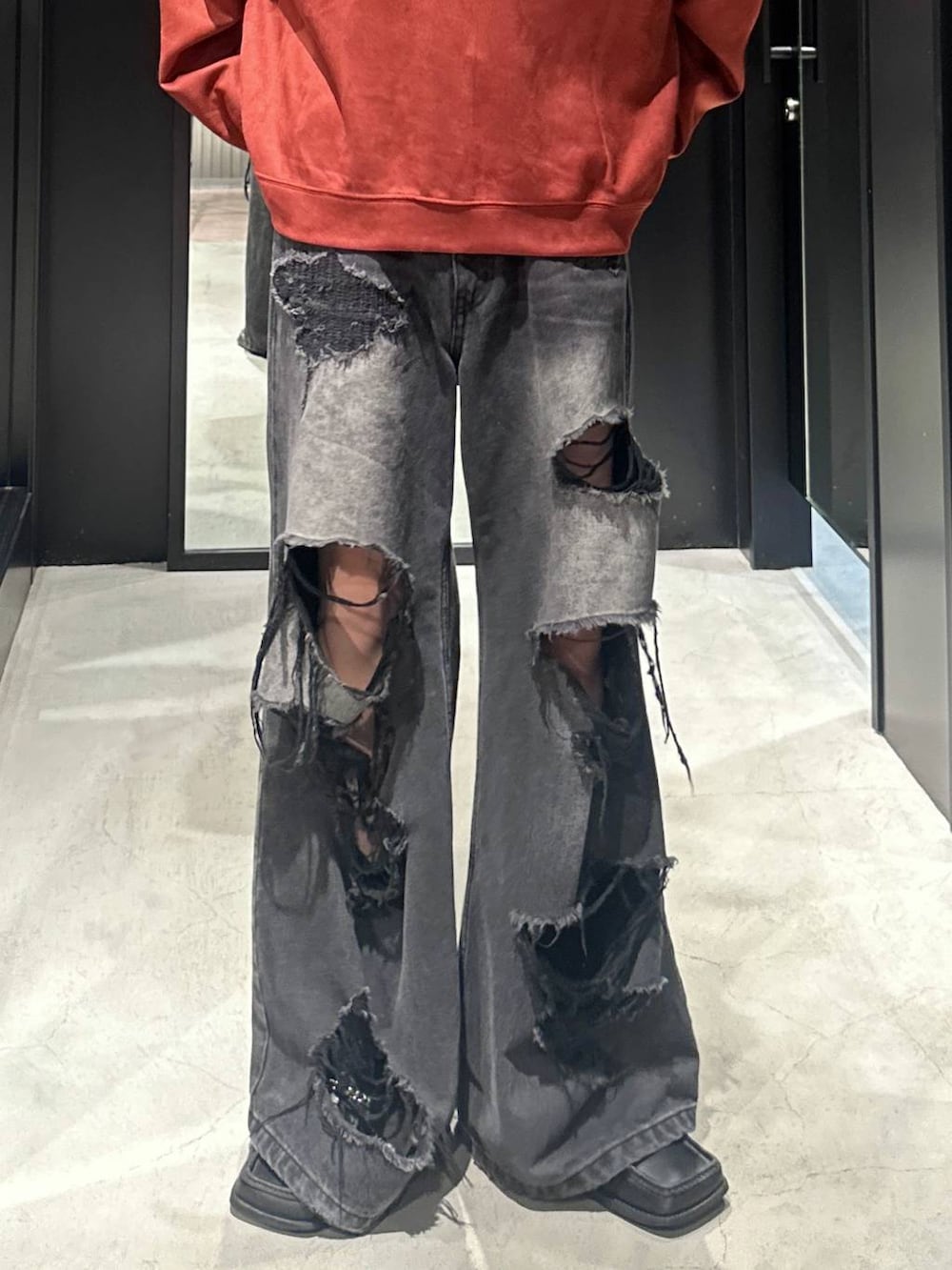 ブラック系のデニムパンツ、オレンジ系のスウェット、シルバー系のネックレスを着用したメンズの秋コーディネートの3枚目の写真