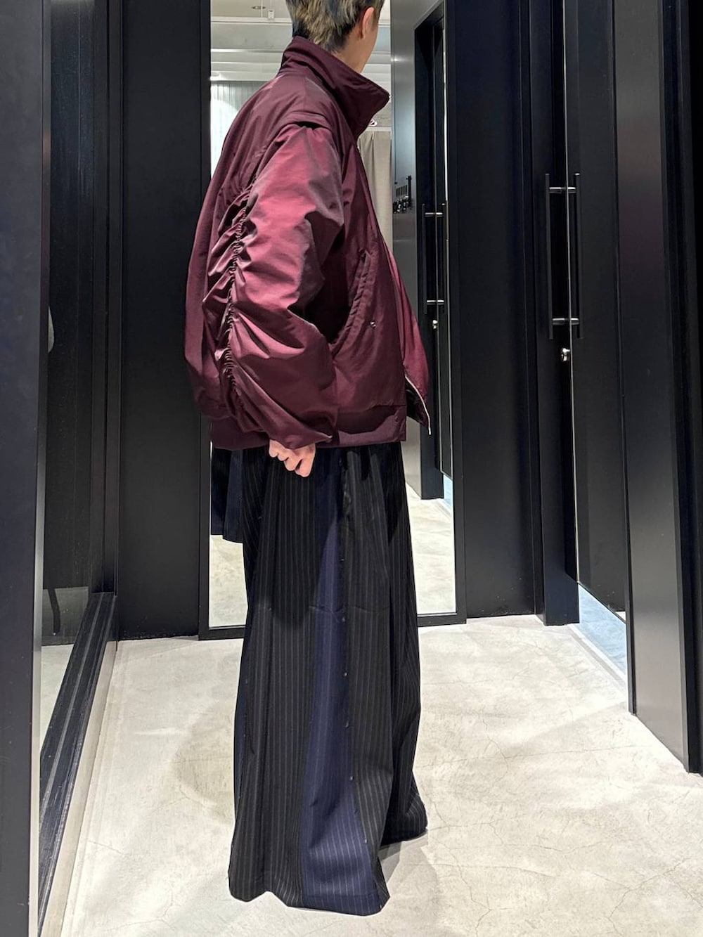 レッド系のブルゾン、ブラック系のその他パンツ、シルバー系のネックレスを着用したメンズの冬コーディネートの2枚目の写真