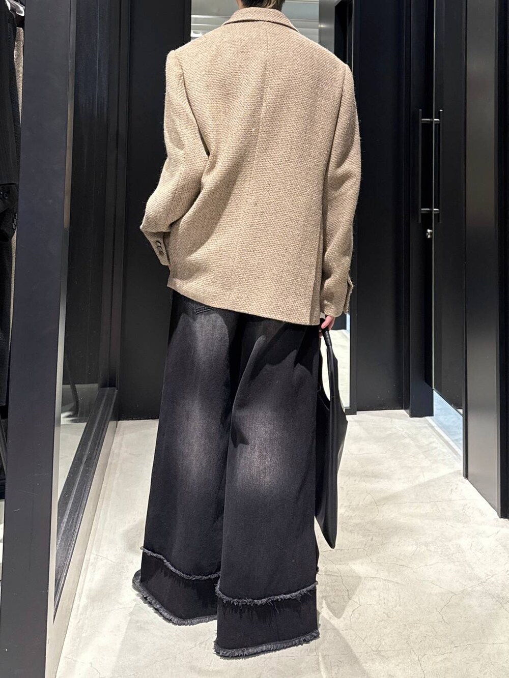 ブラック系のトートバッグ、ベージュ系のテーラードジャケット、ブラック系のデニムパンツを着用したメンズの冬コーディネートの3枚目の写真