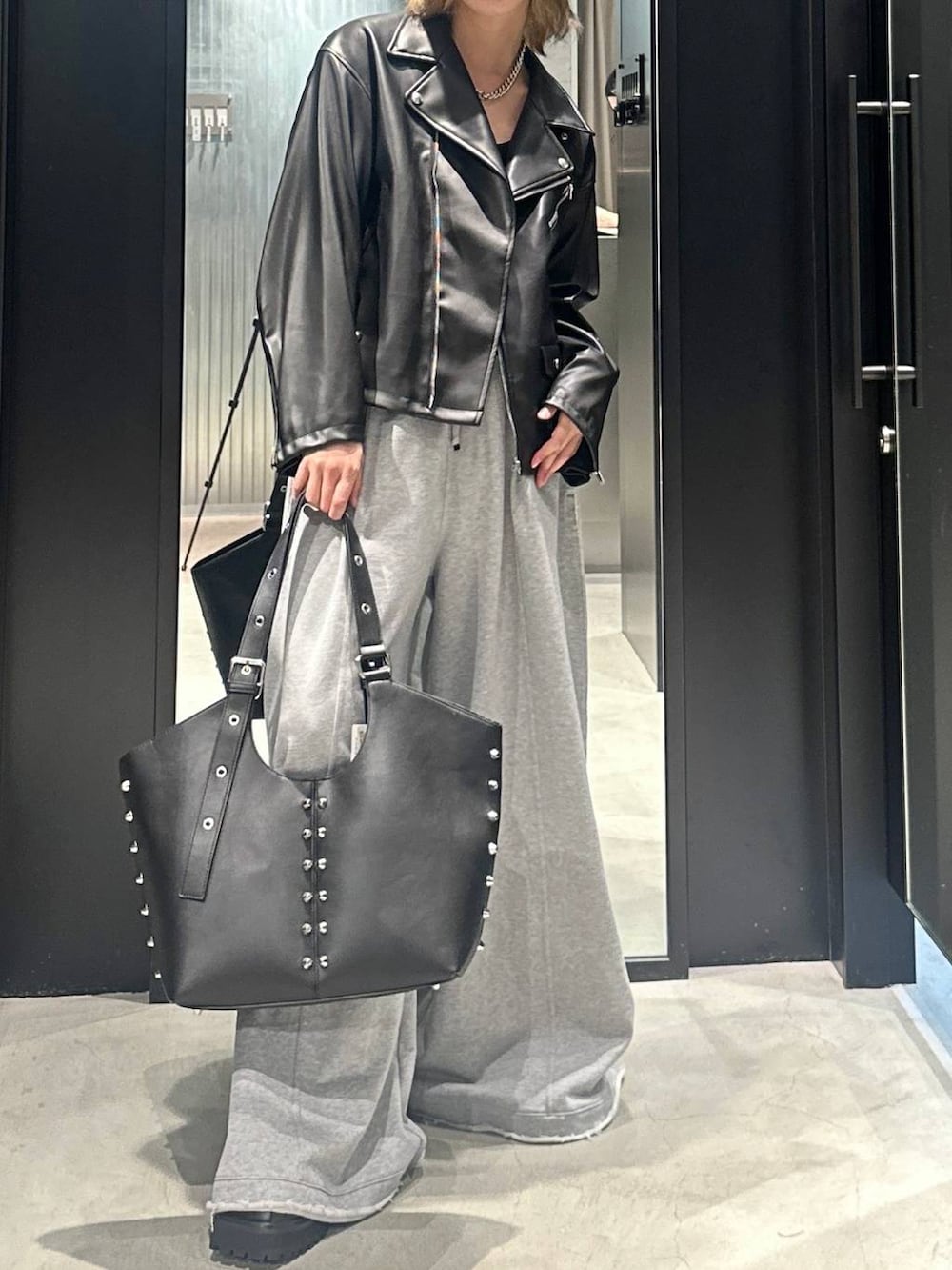 グレー系のスウェットパンツ、ブラック系のライダースジャケット、ブラック系のトートバッグを着用したメンズの秋コーディネートの4枚目の写真