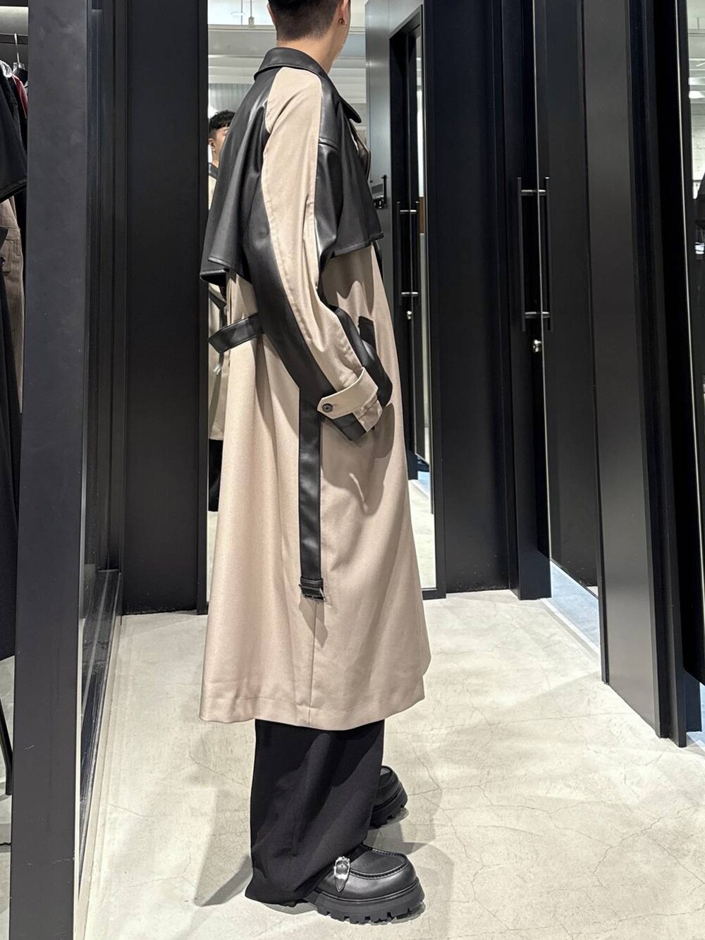 ブラック系のTシャツ/カットソー、ブラック系のドレスシューズ、ベージュ系のトレンチコートを着用したメンズの秋コーディネートの2枚目の写真