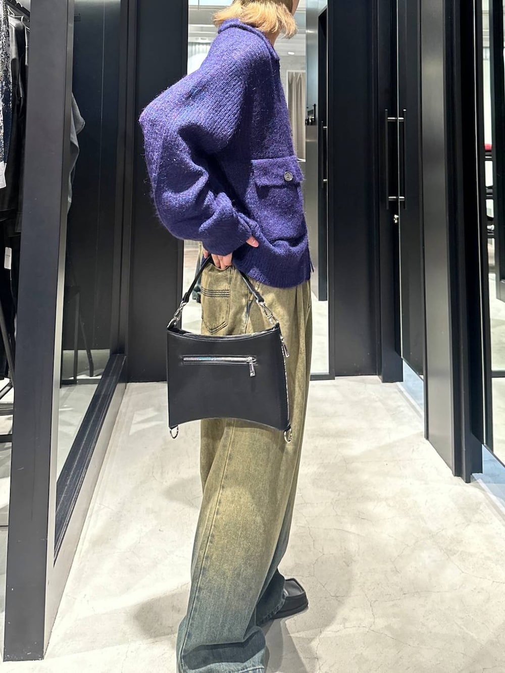 グリーン系のデニムパンツ、ブラック系のショルダーバッグ、ブルー系のニット/セーターを着用したメンズの秋コーディネートの3枚目の写真