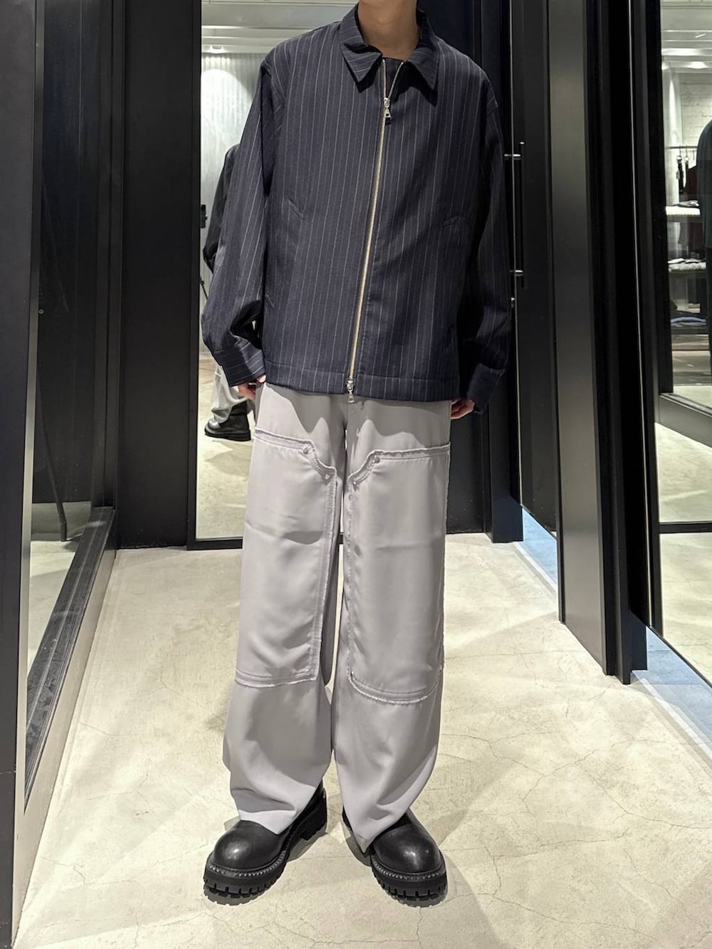 ブルー系のブルゾン、ブラック系のブーツ、シルバー系のネックレスを着用したメンズの秋コーディネートの4枚目の写真