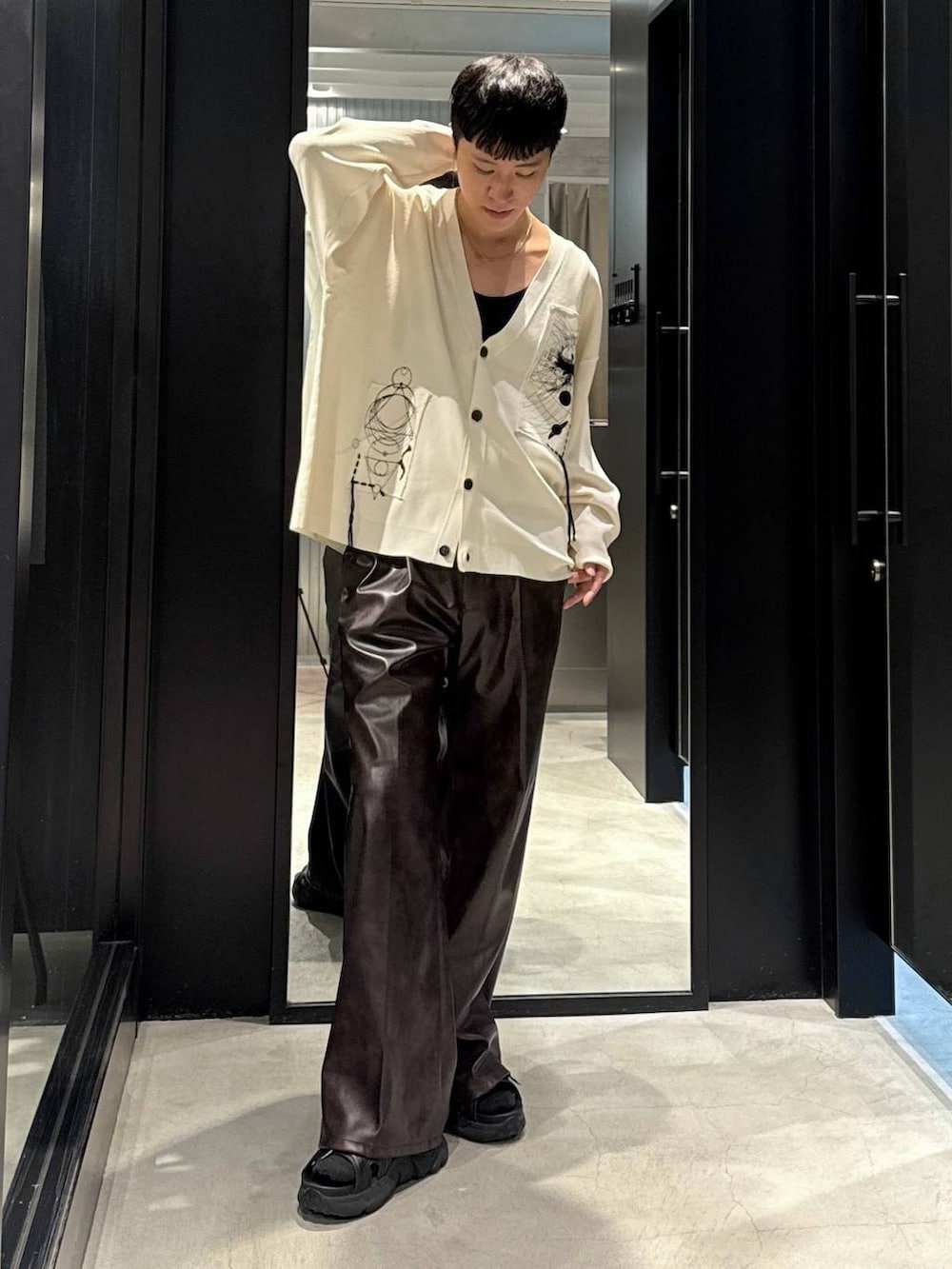 ブラック系のサンダル、ブラック系のタンクトップ、ブラウン系のスラックスを着用したメンズの夏コーディネートの4枚目の写真