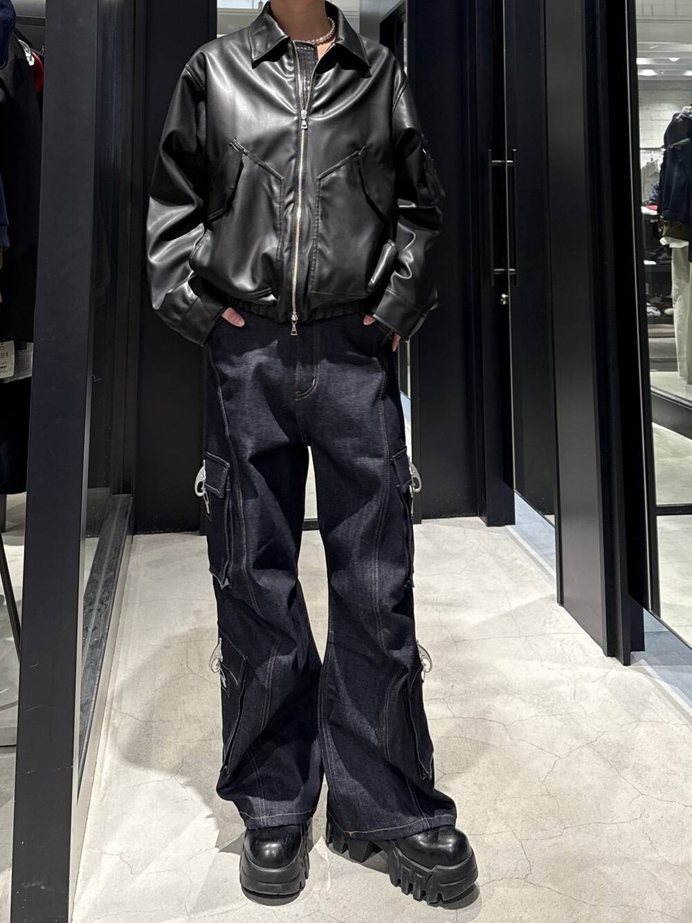 ブラック系のブルゾン、ブルー系のデニムパンツ、ホワイト系のネックレスを着用したメンズの冬コーディネートの4枚目の写真