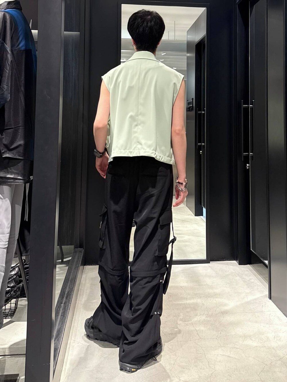 ブラック系のサンダル、グリーン系のベスト、ブラック系のカーゴパンツを着用したメンズの夏コーディネートの2枚目の写真