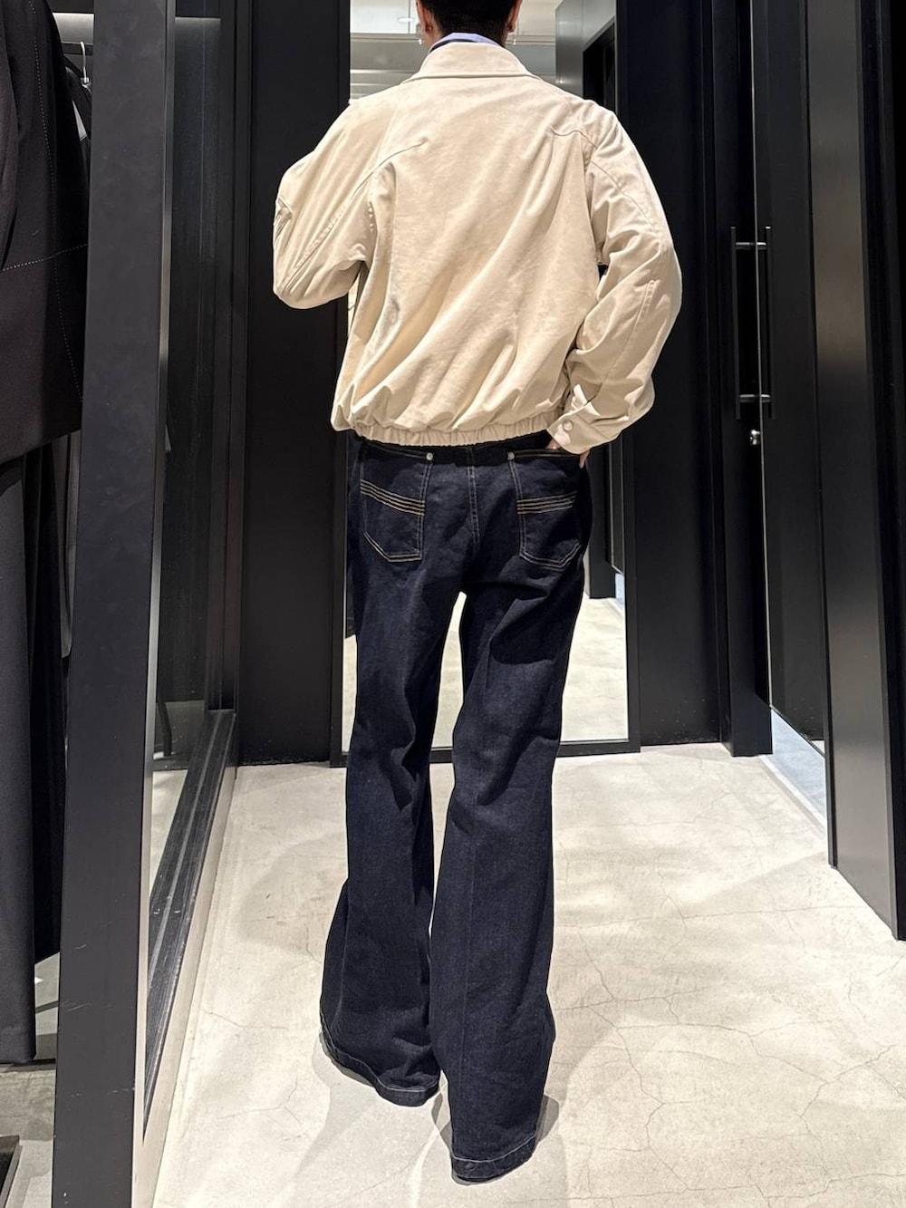 ベージュ系のブルゾン、ブラック系のブーツ、ブルー系のデニムパンツを着用したメンズの冬コーディネートの3枚目の写真