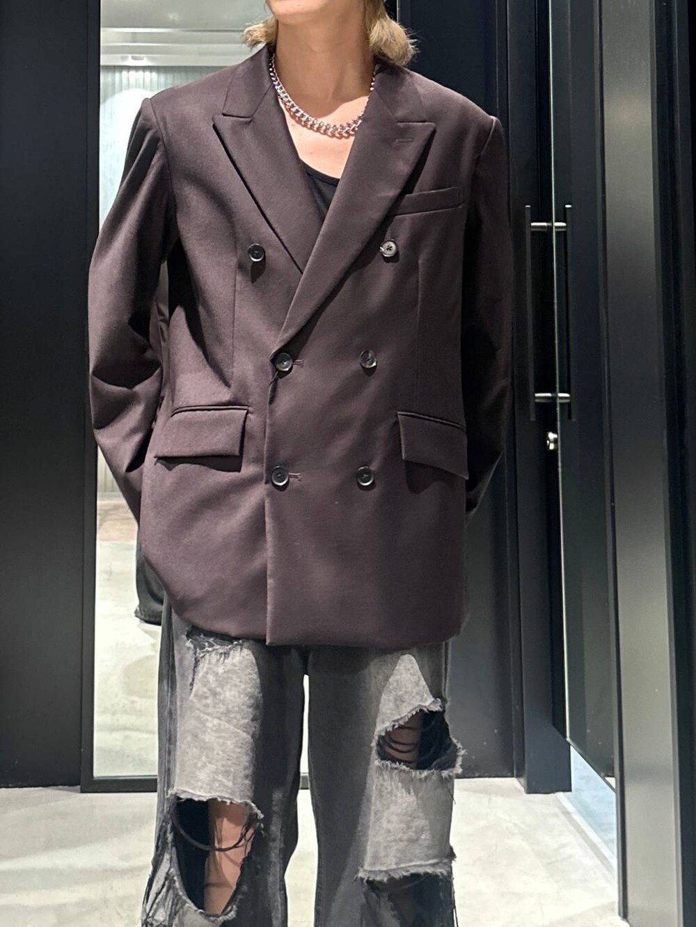 ブラック系のデニムパンツ、ブラウン系のテーラードジャケット、シルバー系のネックレスを着用したメンズの秋コーディネートの3枚目の写真