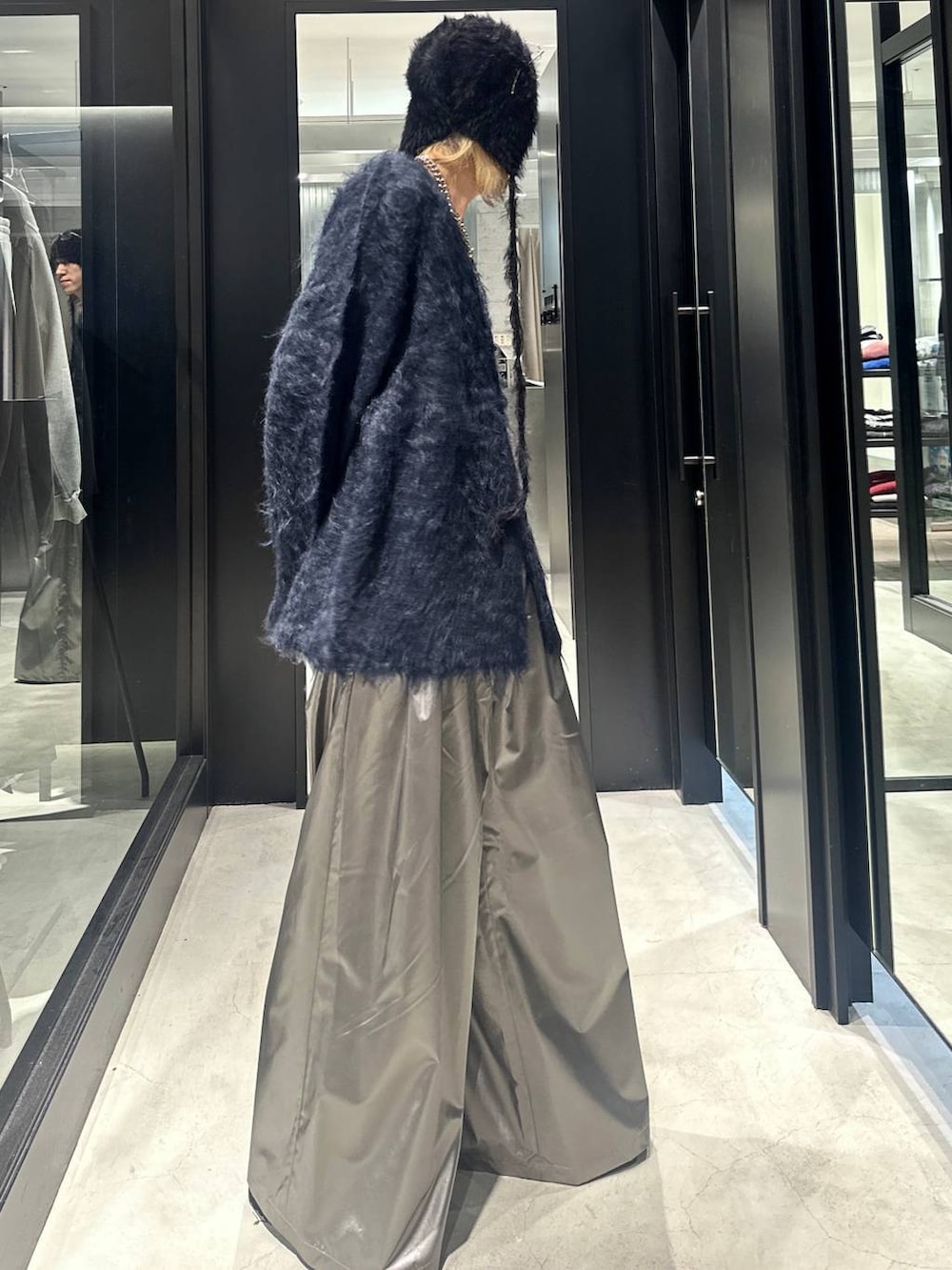 シルバー系のスラックス、ブルー系のカーディガン/ボレロ、ブラック系のドレスシューズを着用したメンズの秋コーディネートの3枚目の写真