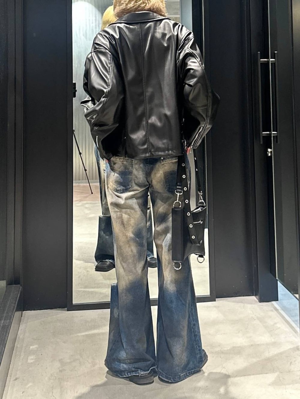 ブラック系のショルダーバッグ、ブラック系のライダースジャケット、ブルー系のデニムパンツを着用したメンズの秋コーディネートの3枚目の写真