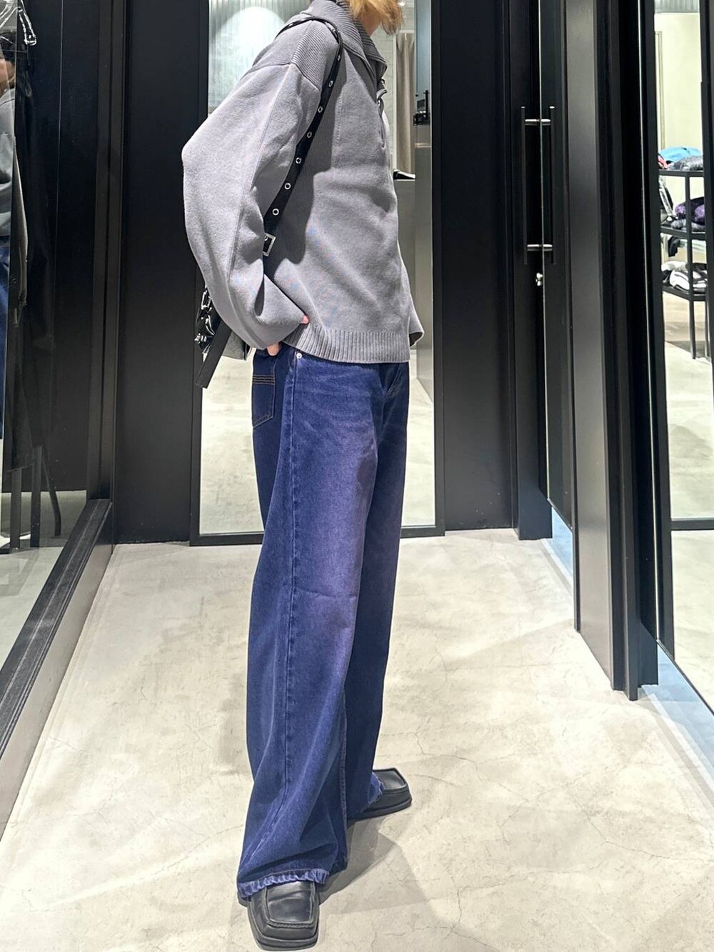 パープル系のデニムパンツ、グレー系のニット/セーター、ブラック系のショルダーバッグを着用したメンズの秋コーディネートの2枚目の写真