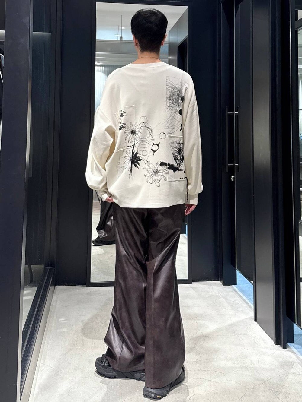 ブラック系のサンダル、ブラック系のタンクトップ、ブラウン系のスラックスを着用したメンズの夏コーディネートの3枚目の写真