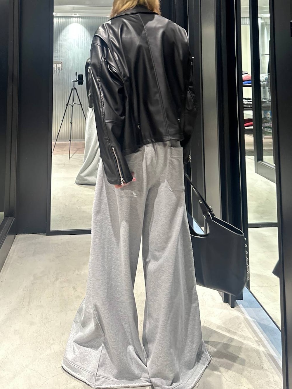 グレー系のスウェットパンツ、ブラック系のライダースジャケット、ブラック系のトートバッグを着用したメンズの秋コーディネートの3枚目の写真