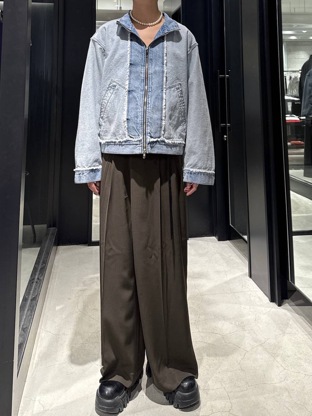 ブルー系のブルゾン、ブラウン系のスラックス、ホワイト系のネックレスを着用したメンズの冬コーディネートの4枚目の写真