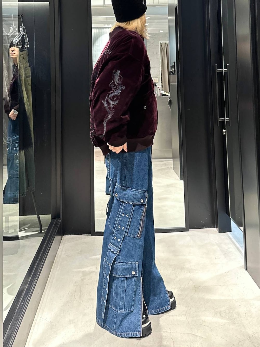 レッド系のブルゾン、ブラック系のその他シューズ、ブルー系のデニムパンツを着用したメンズの秋コーディネートの3枚目の写真