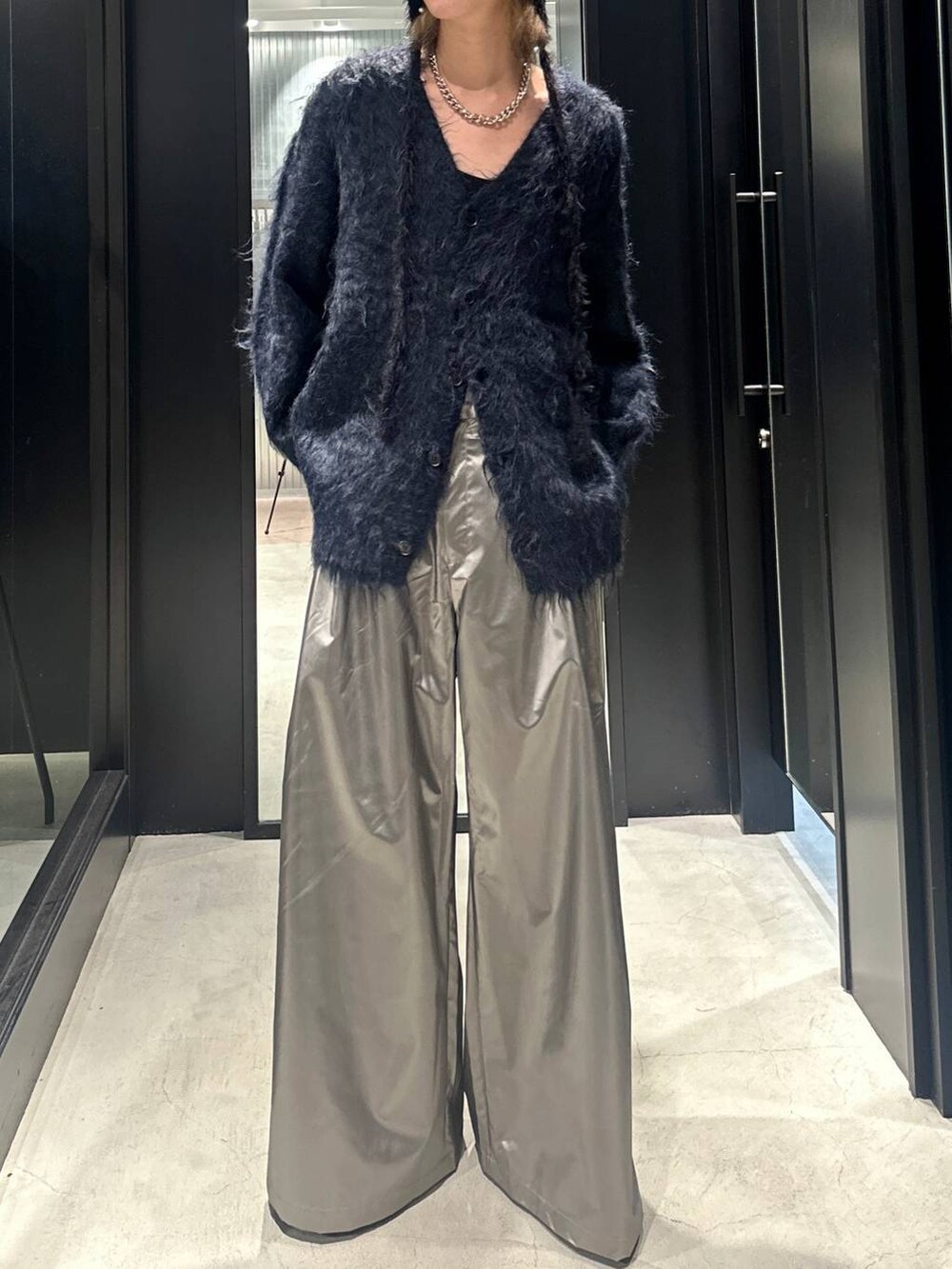 シルバー系のスラックス、ブルー系のカーディガン/ボレロ、ブラック系のドレスシューズを着用したメンズの秋コーディネートの2枚目の写真