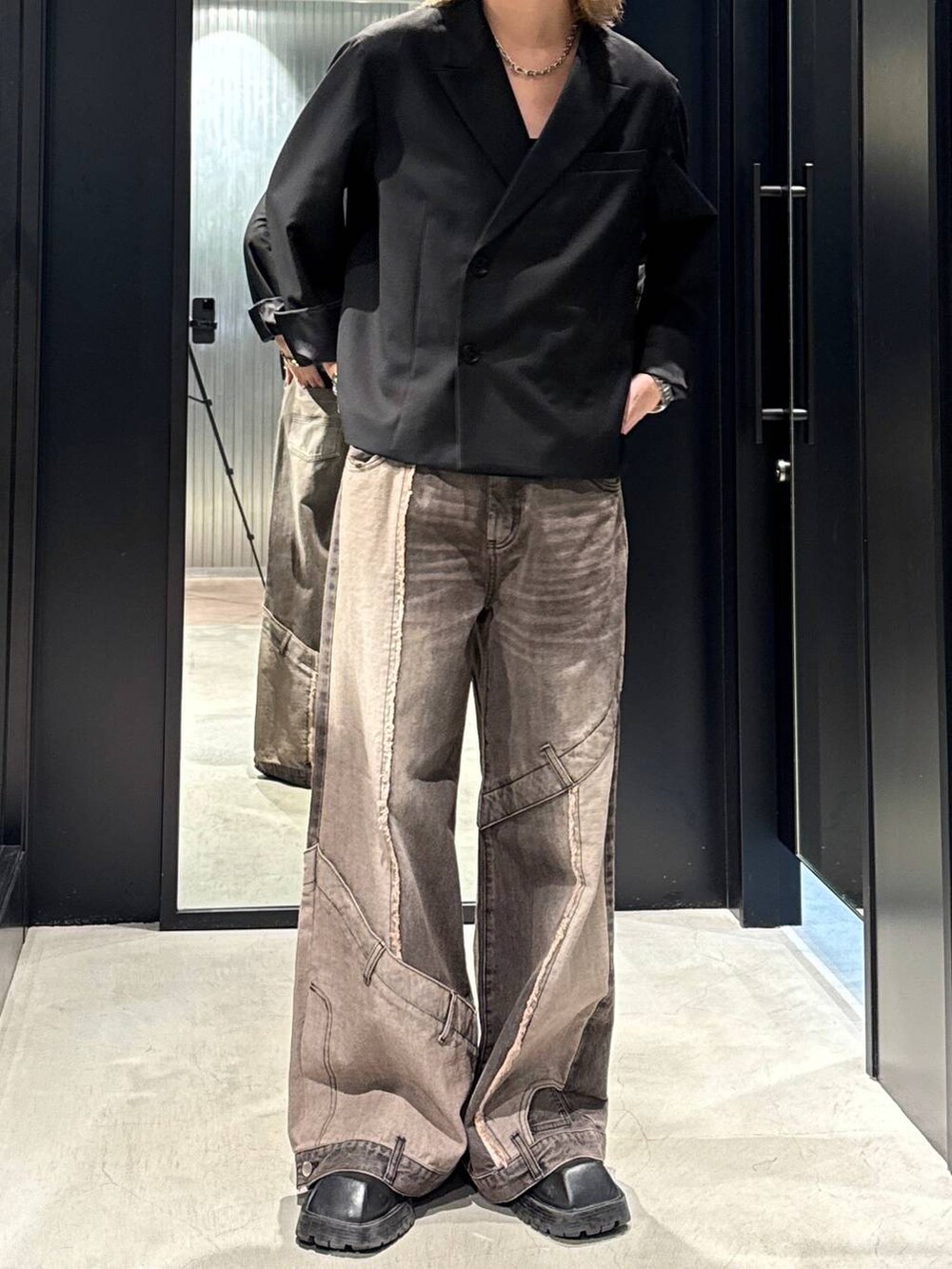 ブラウン系のデニムパンツ、ブラック系のテーラードジャケット、ブラック系のキャップを着用したメンズの秋コーディネートの3枚目の写真