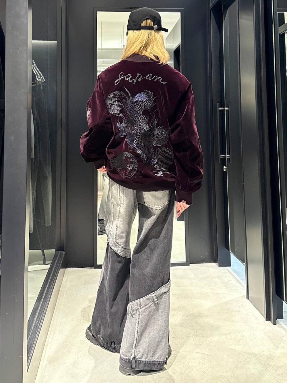 ブラック系のデニムパンツ、レッド系のブルゾン、ブラック系のキャップを着用したメンズの秋コーディネートの3枚目の写真