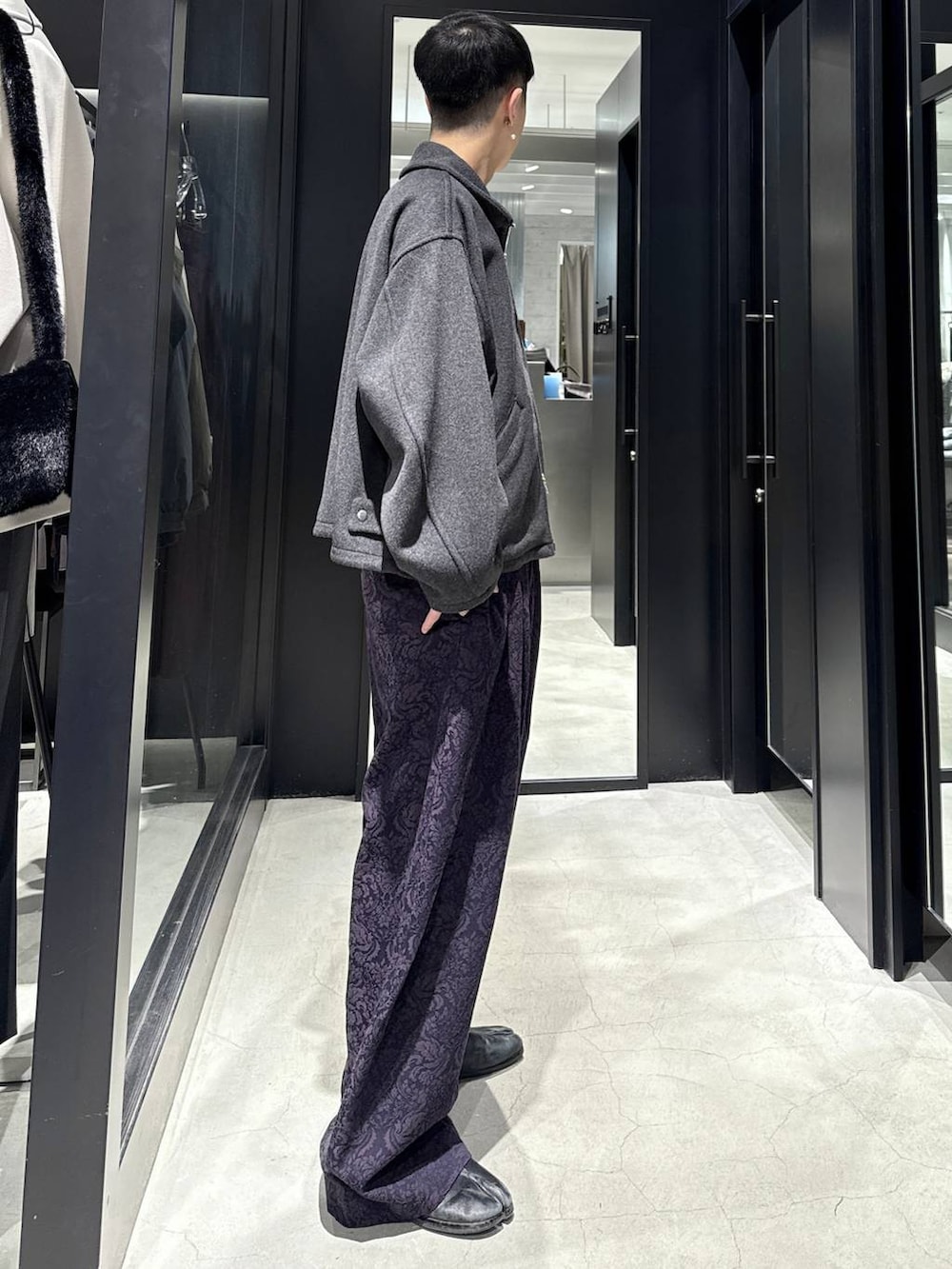 グレー系のブルゾン、パープル系のスラックスを着用したメンズの秋コーディネートの2枚目の写真