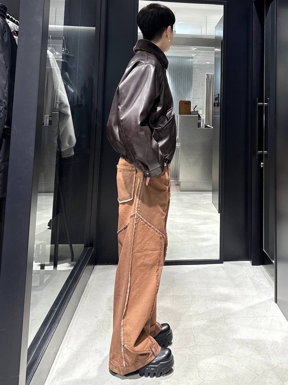 ブラウン系のブルゾン、オレンジ系のデニムパンツ、シルバー系のネックレスを着用したメンズの冬コーディネートの2枚目の写真