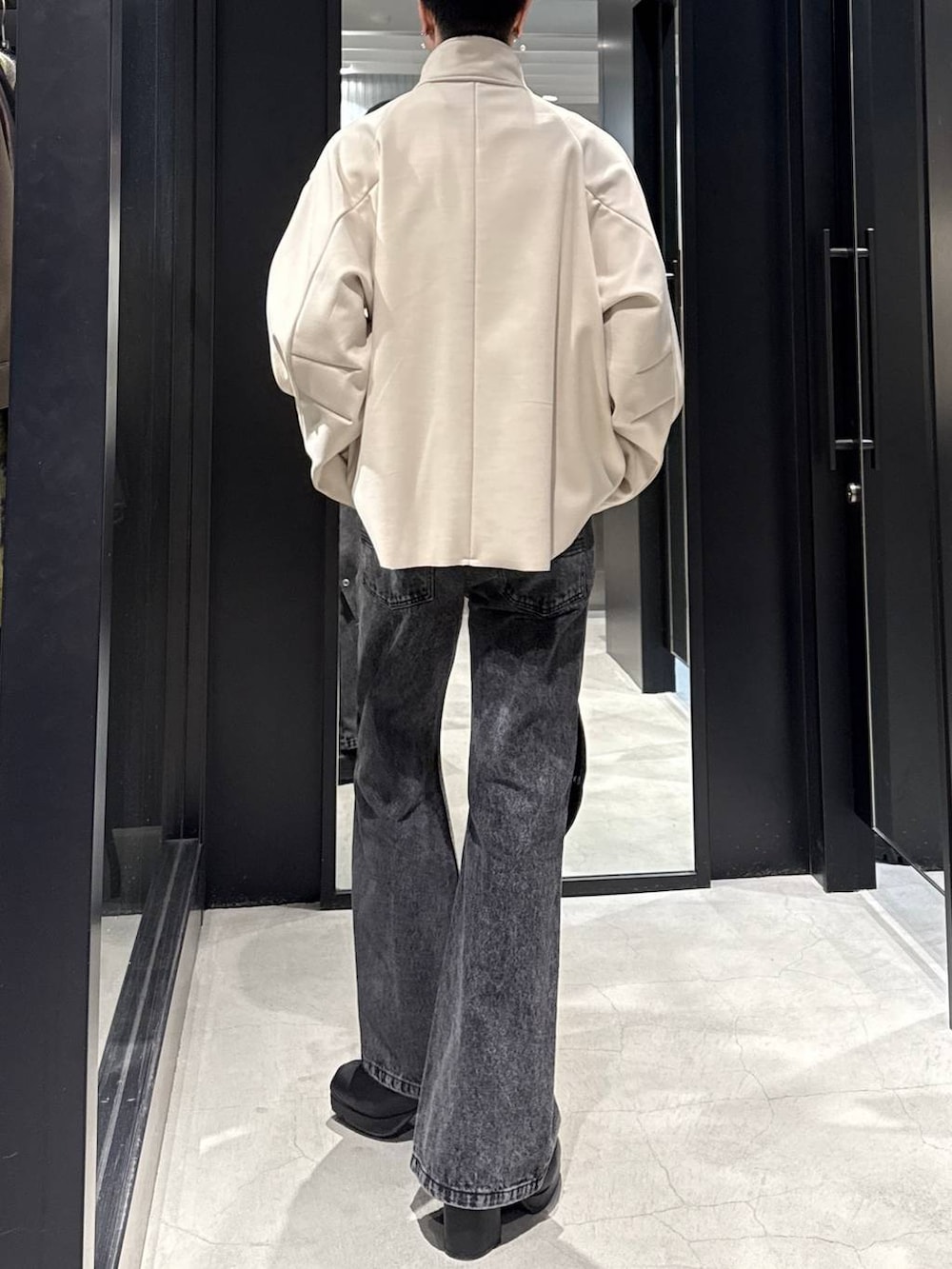 ブラック系のブーツ、ホワイト系のブルゾン、ブラック系のデニムパンツを着用したメンズの冬コーディネートの3枚目の写真