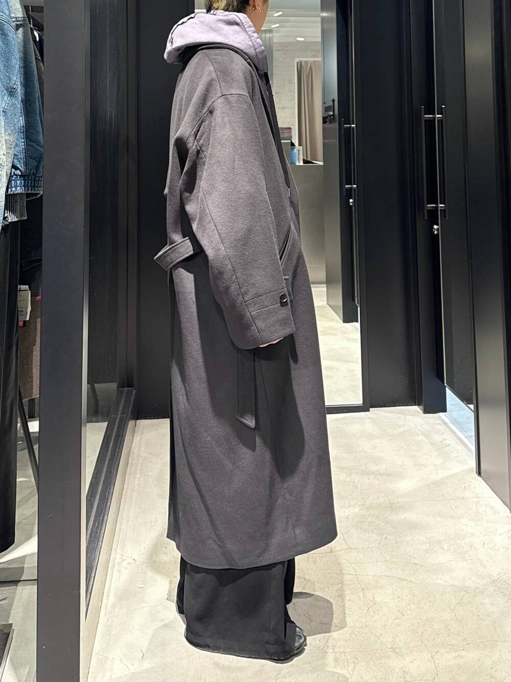 グレー系のトレンチコート、ブラック系のスラックス、パープル系のパーカーを着用したメンズの冬コーディネートの2枚目の写真