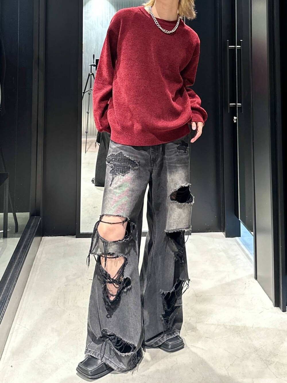 ブラック系のデニムパンツ、レッド系のニット/セーター、ブラック系のキャップを着用したメンズの秋コーディネートの5枚目の写真