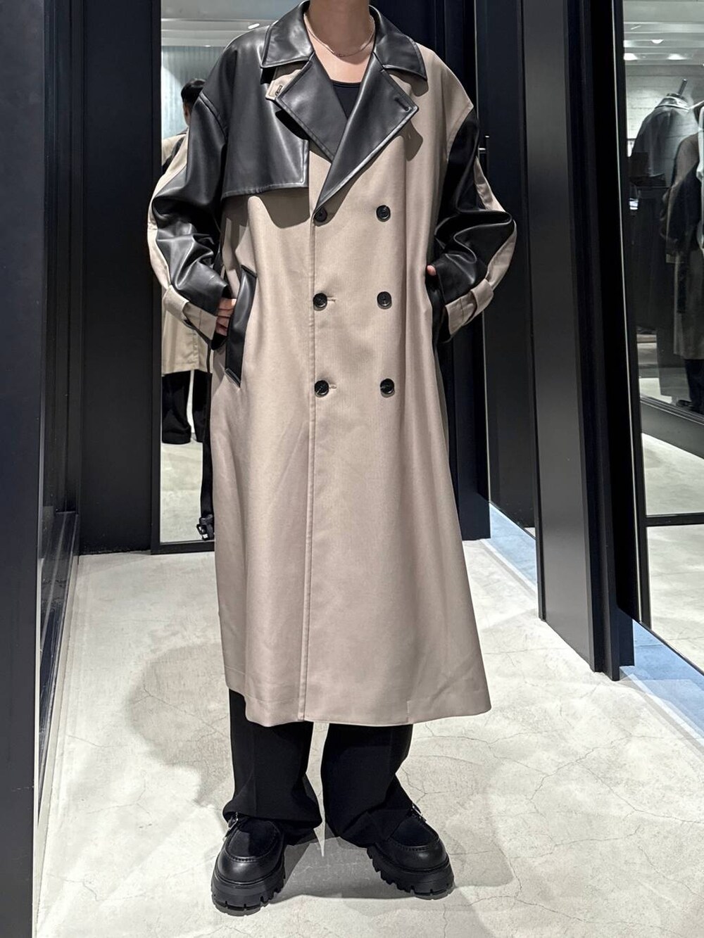 ブラック系のTシャツ/カットソー、ブラック系のドレスシューズ、ベージュ系のトレンチコートを着用したメンズの秋コーディネートの4枚目の写真