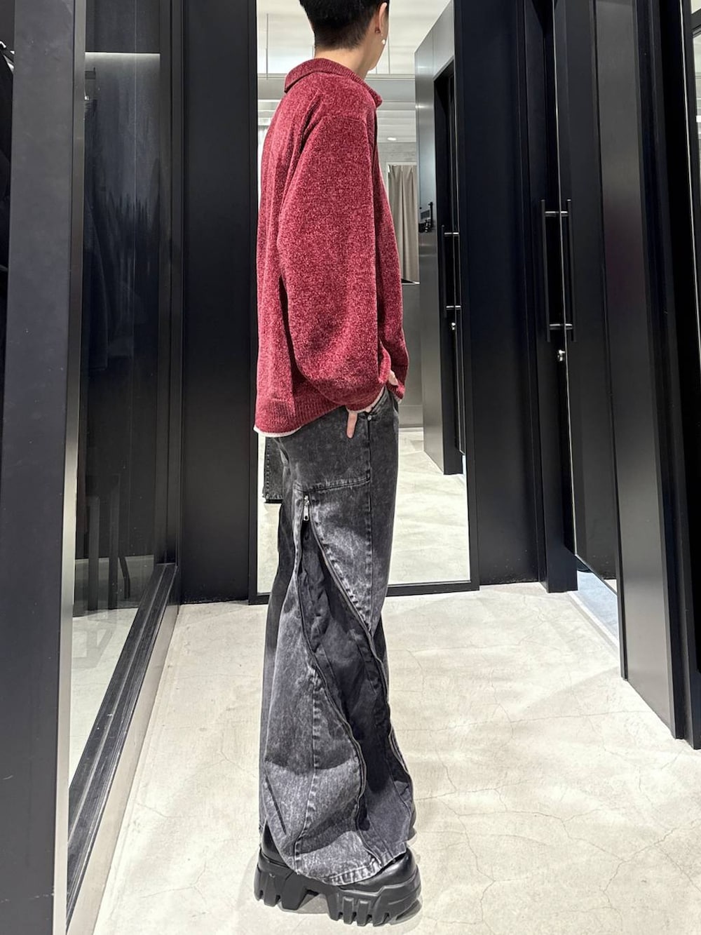 レッド系のニット/セーター、ブラック系のデニムパンツ、シルバー系のネックレスを着用したメンズの冬コーディネートの2枚目の写真