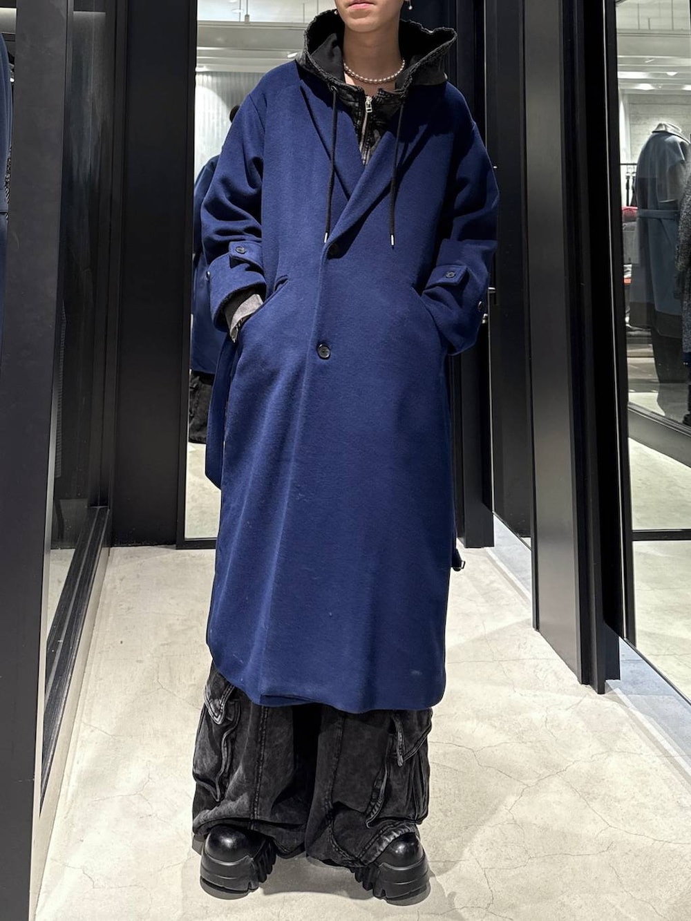 ブルー系のチェスターコート、ブラック系のパーカー、ブラック系のスウェットパンツを着用したメンズの冬コーディネートの4枚目の写真