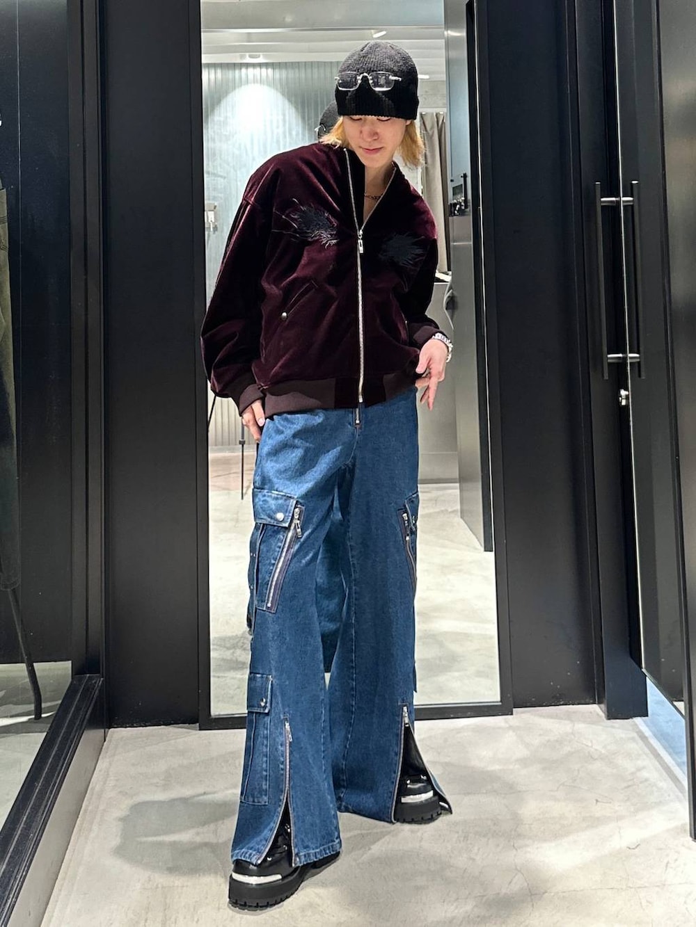 レッド系のブルゾン、ブラック系のその他シューズ、ブルー系のデニムパンツを着用したメンズの秋コーディネートの2枚目の写真