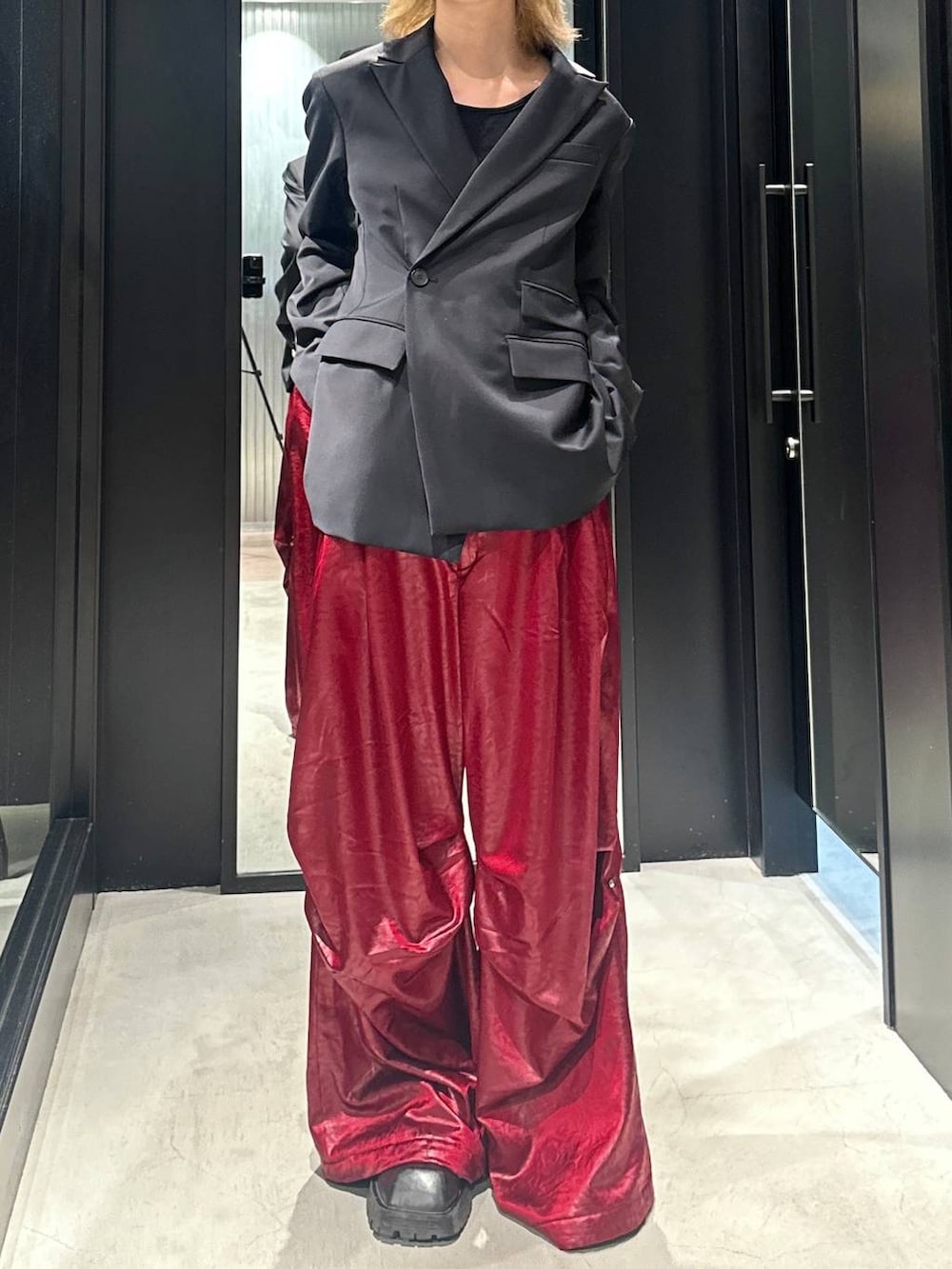 ブラック系のテーラードジャケット、レッド系のその他パンツ、ブラック系のキャップを着用したメンズの秋コーディネートの3枚目の写真