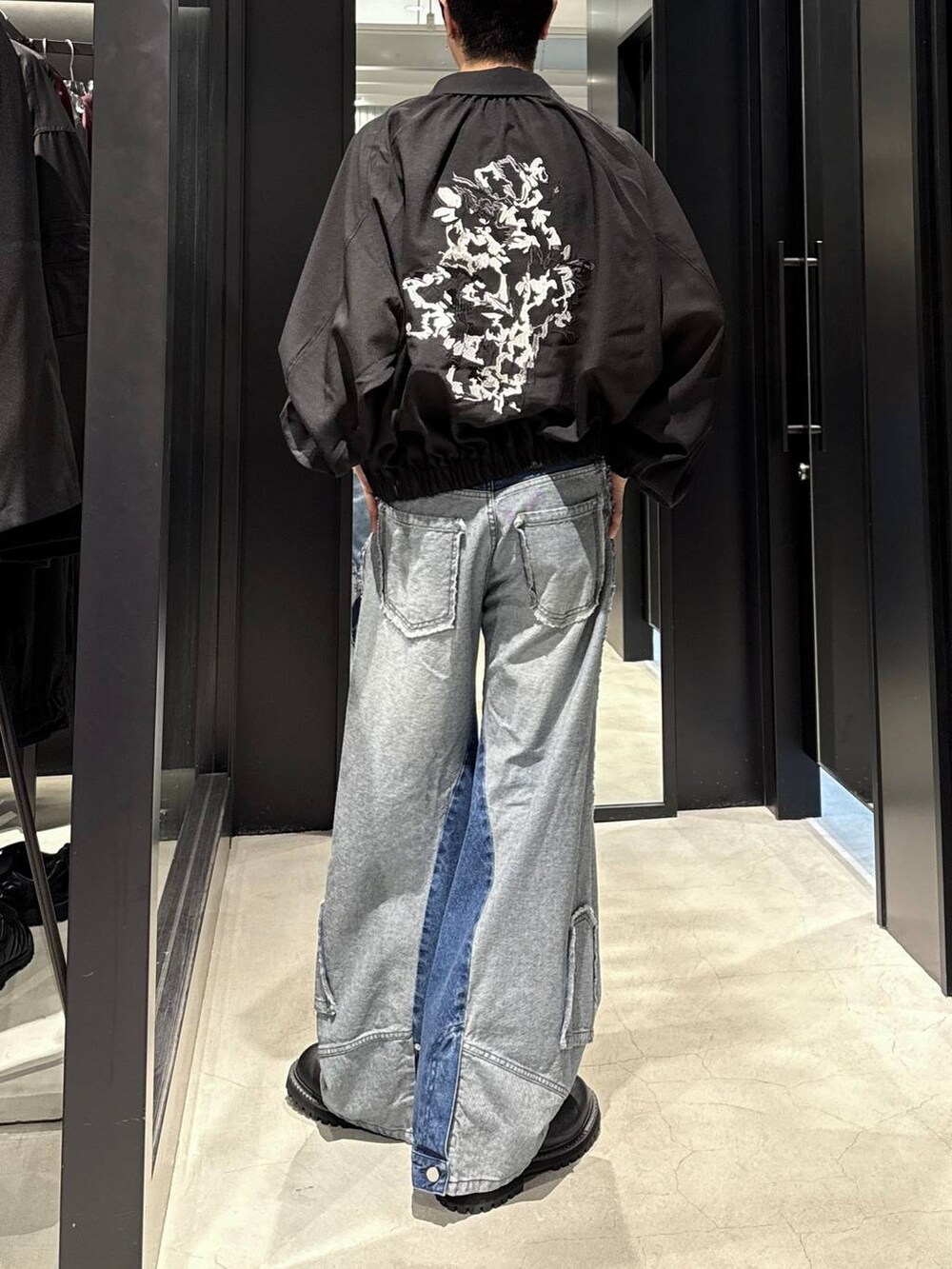 ホワイト系のTシャツ/カットソー、ブルー系のデニムパンツ、ブラック系のブーツを着用したメンズの秋コーディネートの3枚目の写真