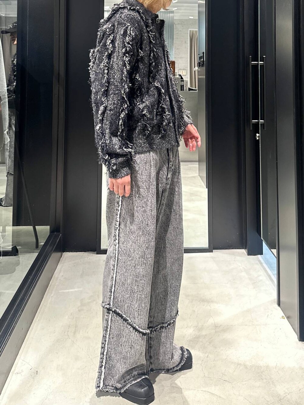 グレー系のデニムパンツ、ブラック系のブーツ、ブラック系のブルゾンを着用したメンズの秋コーディネートの2枚目の写真