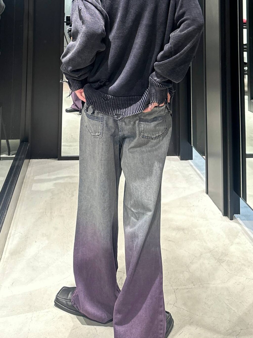 パープル系のデニムパンツ、ブラック系のニット/セーター、シルバー系のネックレスを着用したメンズの秋コーディネートの5枚目の写真