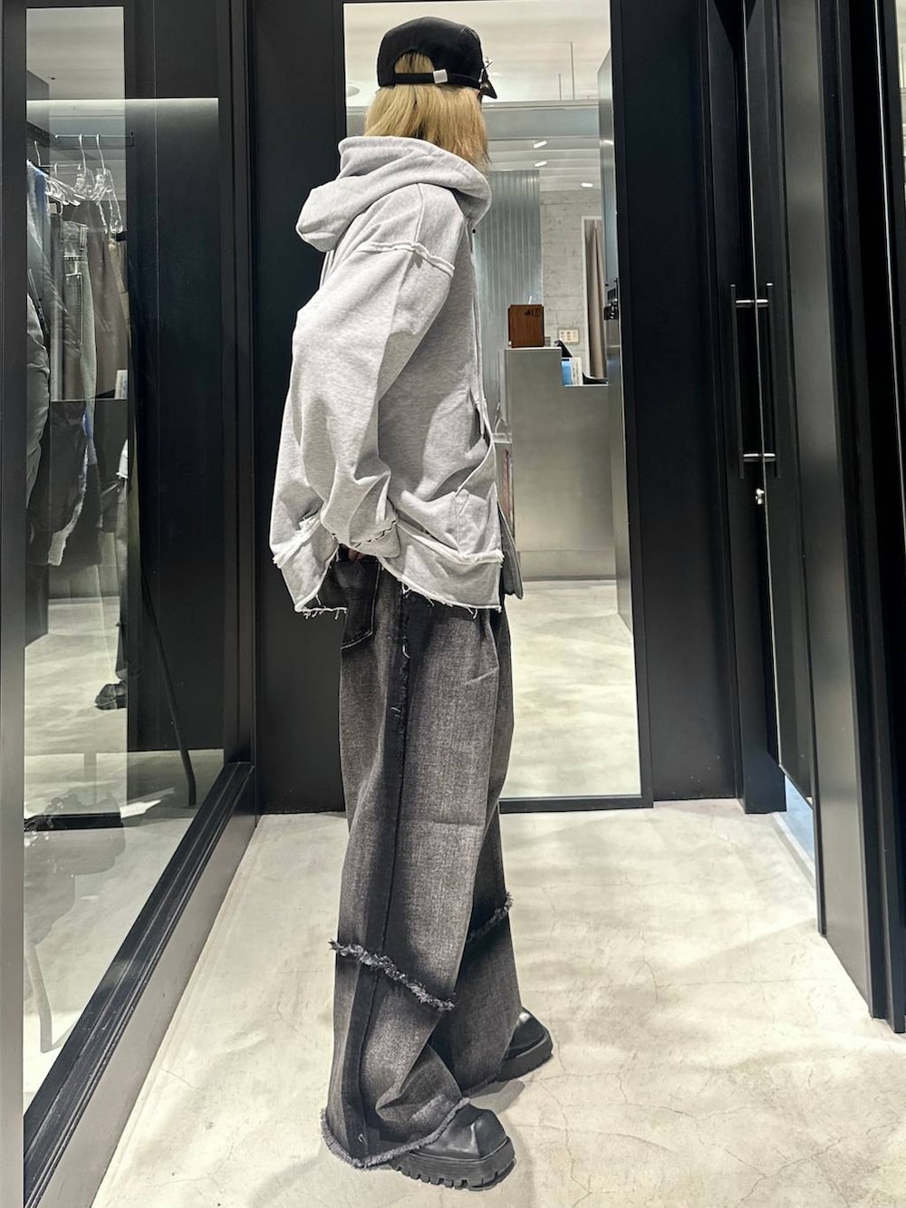 ブラック系のデニムパンツ、グレー系のパーカー、ブラック系のキャップを着用したメンズの秋コーディネートの2枚目の写真