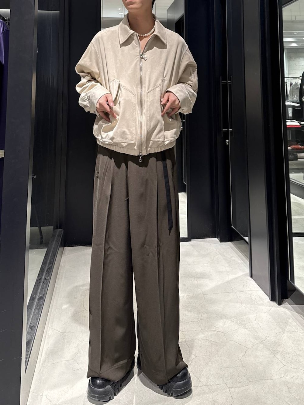 ベージュ系のブルゾン、ブラウン系のスラックス、ホワイト系のネックレスを着用したメンズの冬コーディネートの4枚目の写真