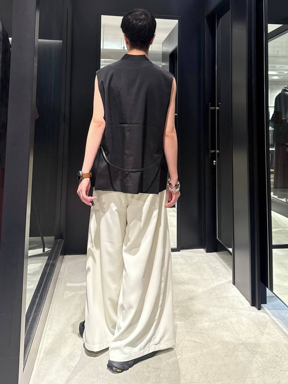 ブラック系のサンダル、ホワイト系のスラックス、ホワイト系のタンクトップを着用したメンズの夏コーディネートの2枚目の写真