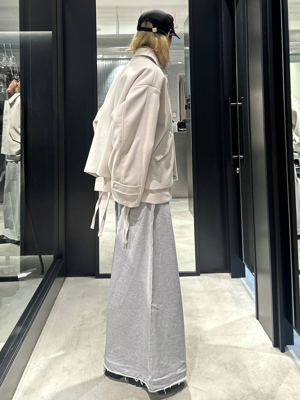 グレー系のスウェットパンツ、ホワイト系のブルゾン、ブラック系のキャップを着用したメンズの秋コーディネートの2枚目の写真