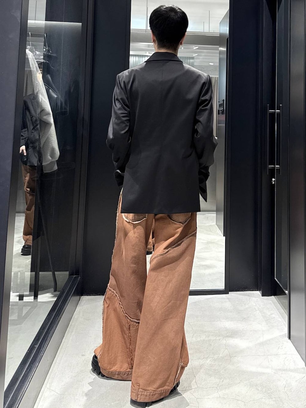 オレンジ系のデニムパンツ、ブラック系のテーラードジャケット、シルバー系のネックレスを着用したメンズの冬コーディネートの3枚目の写真