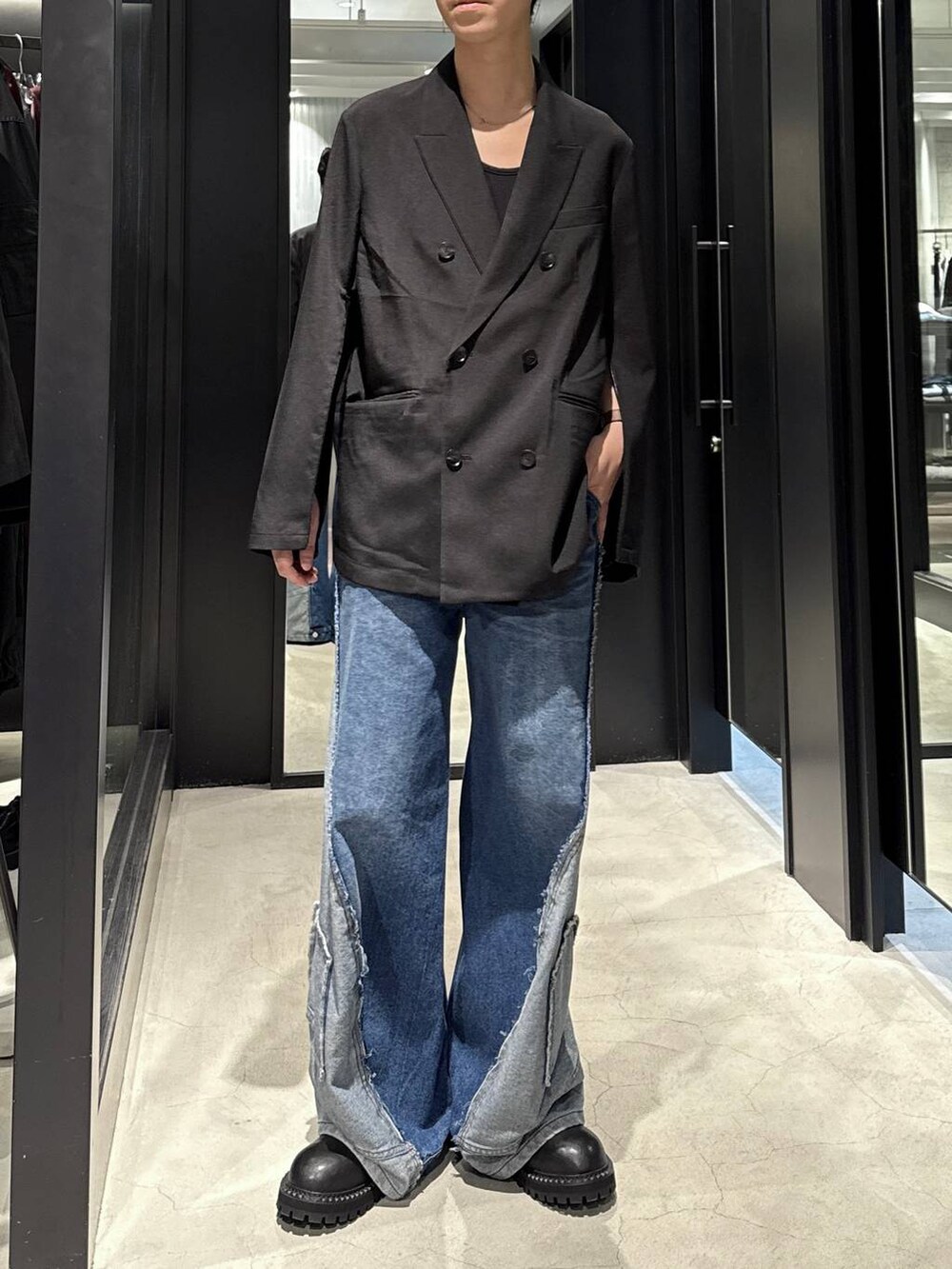 ブラック系のタンクトップ、ブルー系のデニムパンツ、ブラック系のテーラードジャケットを着用したメンズの秋コーディネートの4枚目の写真