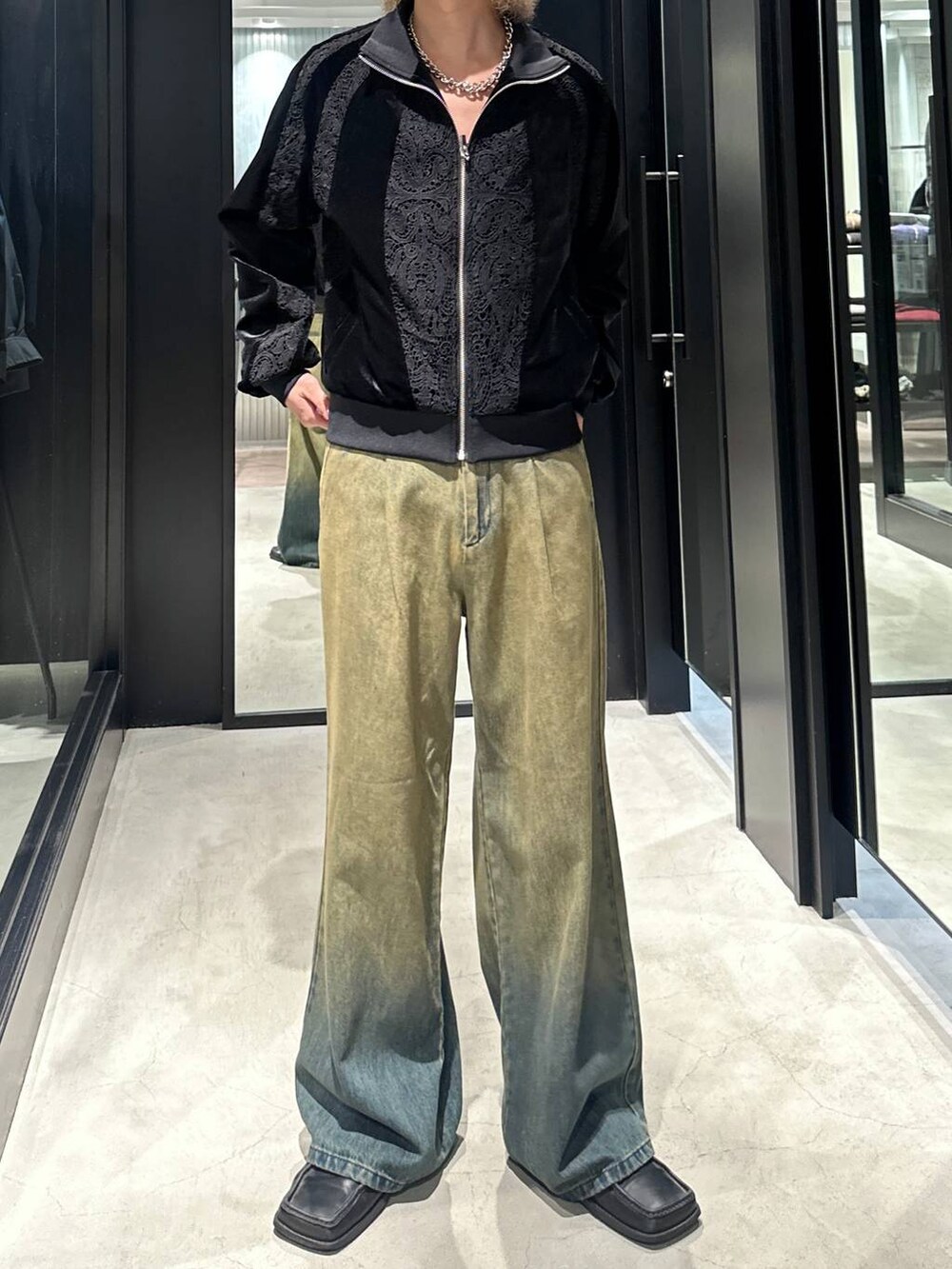グリーン系のデニムパンツ、ブラック系のブルゾン、シルバー系のネックレスを着用したメンズの秋コーディネートの2枚目の写真